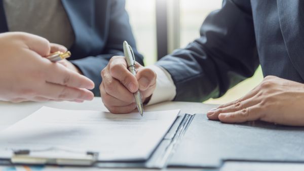 Two male business partners sign a contract to purchase a commercial property.