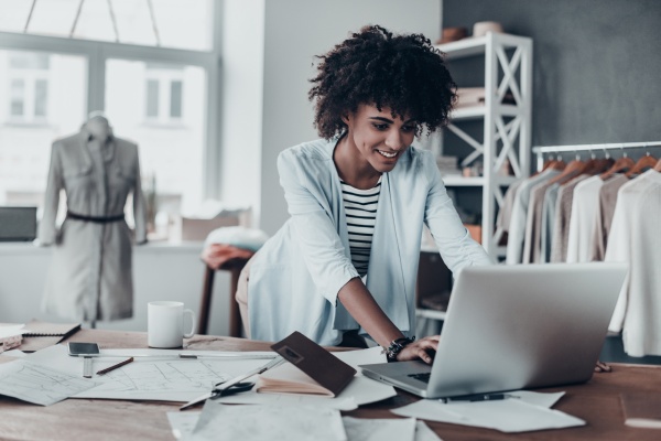 A female business owner uses her laptop to research about selling her clothing business.