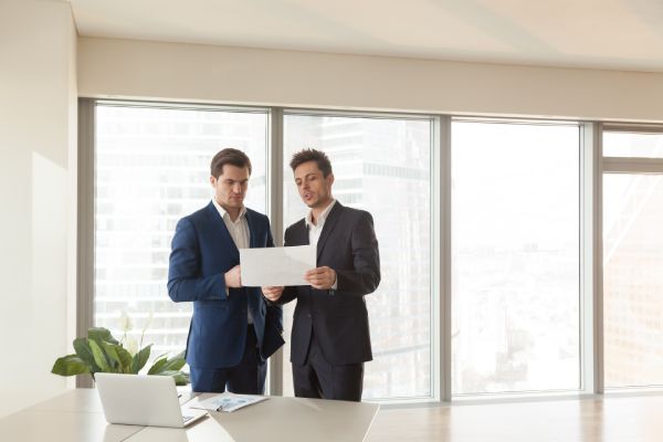 A male business owner consults with a male solicitor in a modern office building.