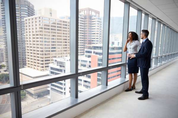 A businesswoman and businessman view an empty office building and discuss the prospect of buying it.