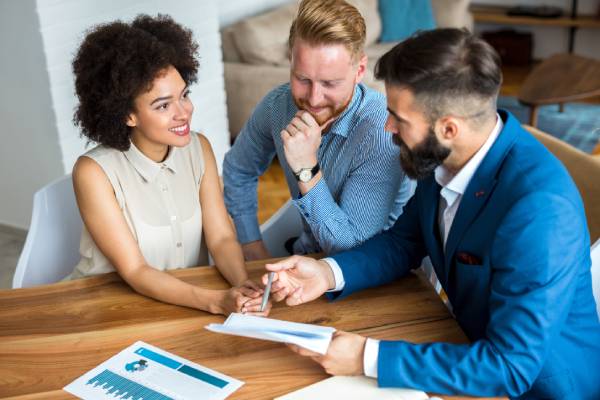 A young smiling couple consult with a solicitor about transferring equity.