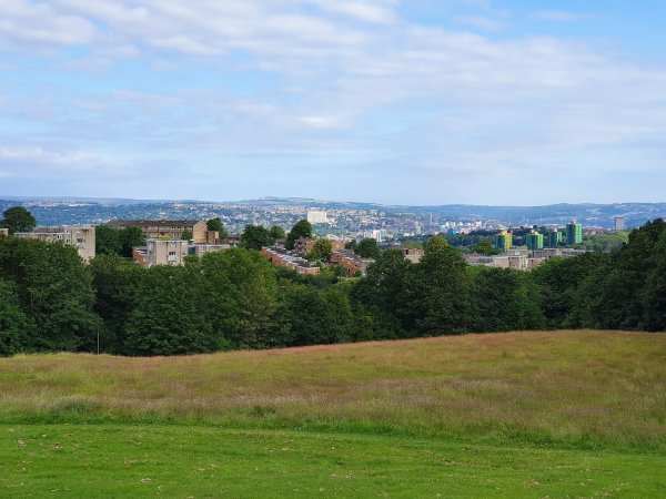 A wide angle view of Sheffield taken from the top of a hill on a sunny day.