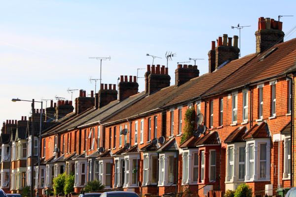 A long row of English terraced houses with a blue sky background.