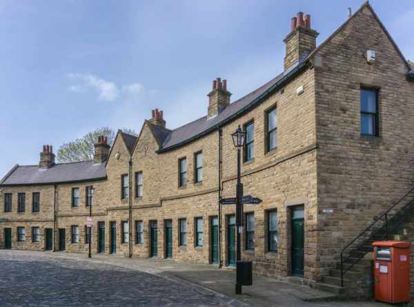 A row of traditional English terraced houses pictured on a sunny day.